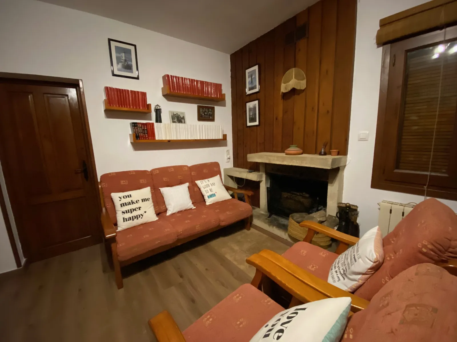 Chimenea de piedra en el salón, junto a sofás y estanterías de madera