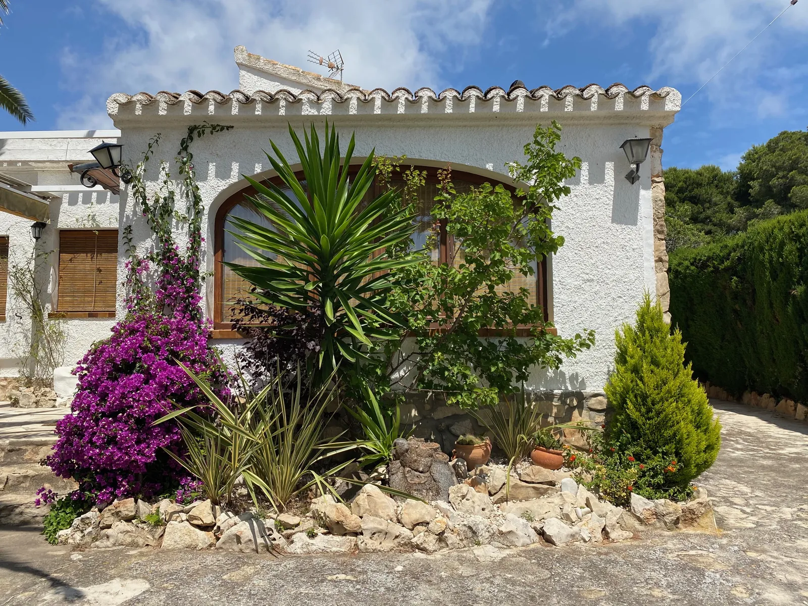Fachada blanca de Casa Els Molins con buganvilla en flor