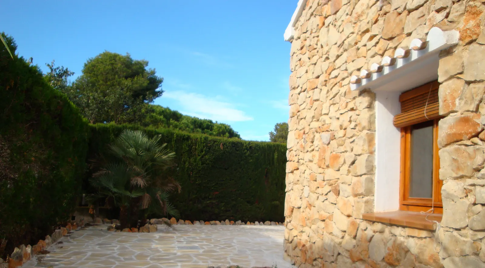 Patio de piedra y seto de cipreses de Casa Els Molins